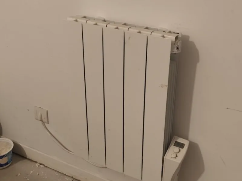 Radiateur électrique posé et raccordé, avec reprises d'enduit autour