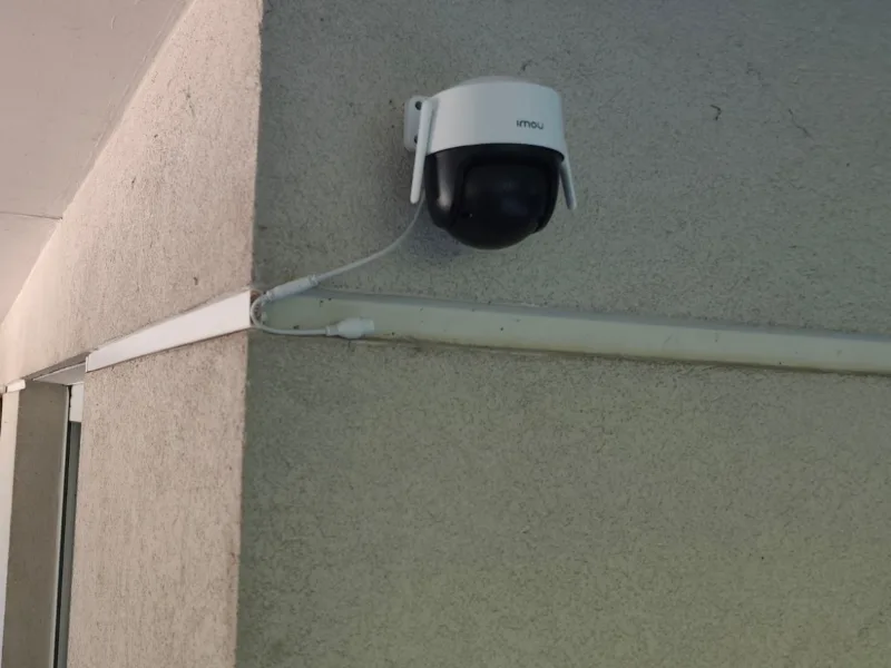 Caméra de surveillance extérieure posée en angle de mur, câble protégé sous goulotte